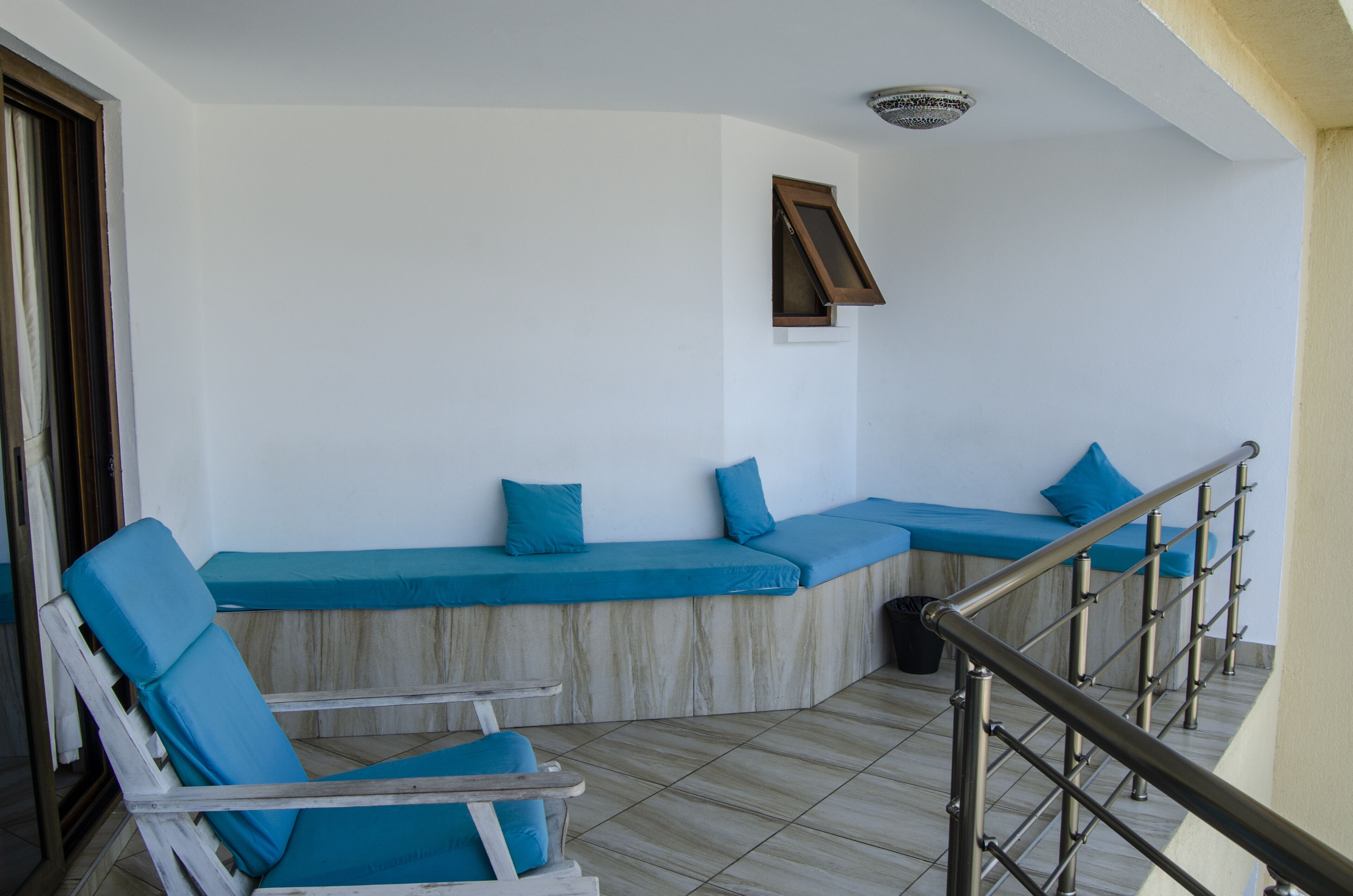 A balcony with a seating area, a small table, and a staircase railing.