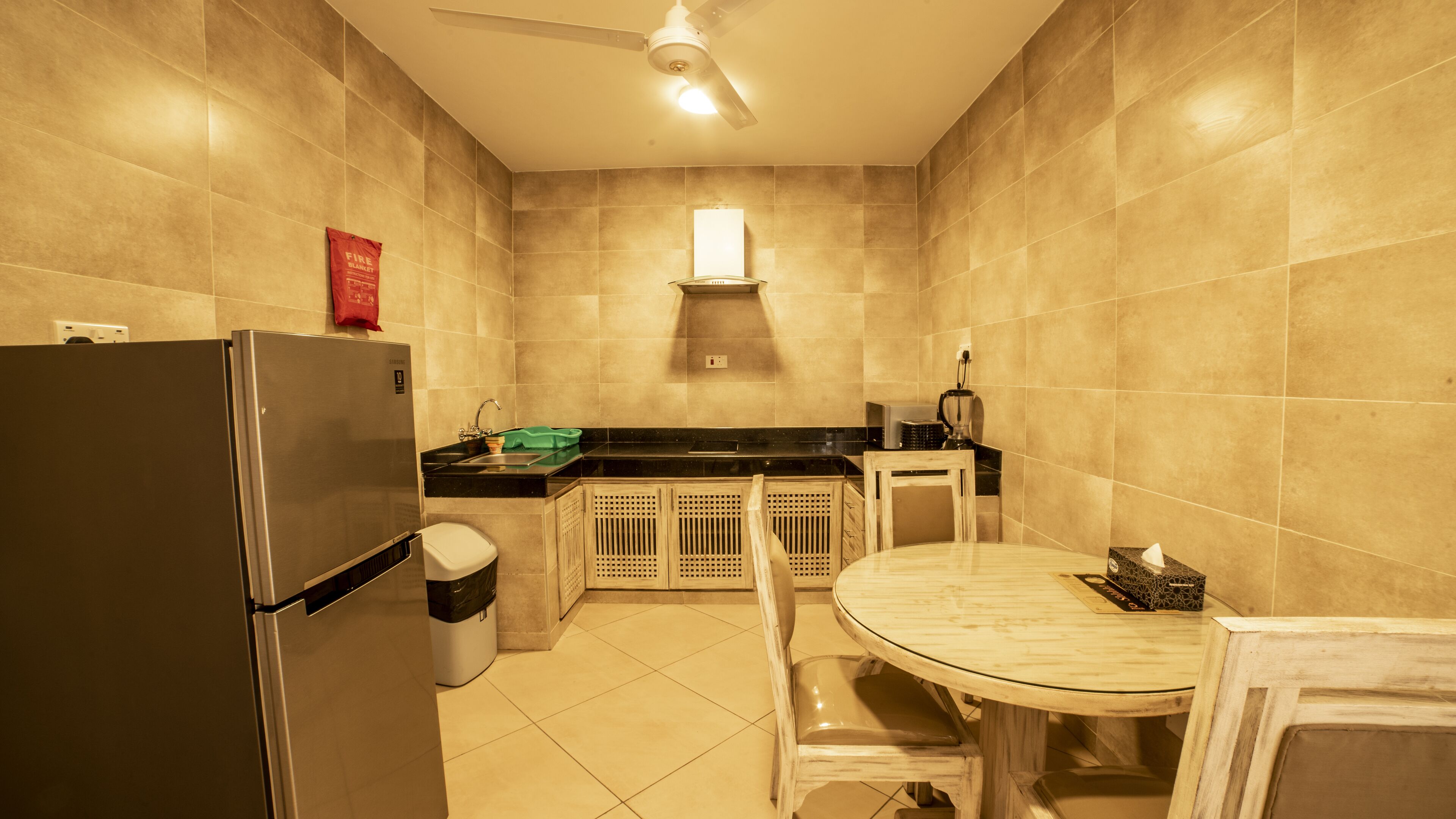 A compact kitchen with a refrigerator, sink, and a small dining table.