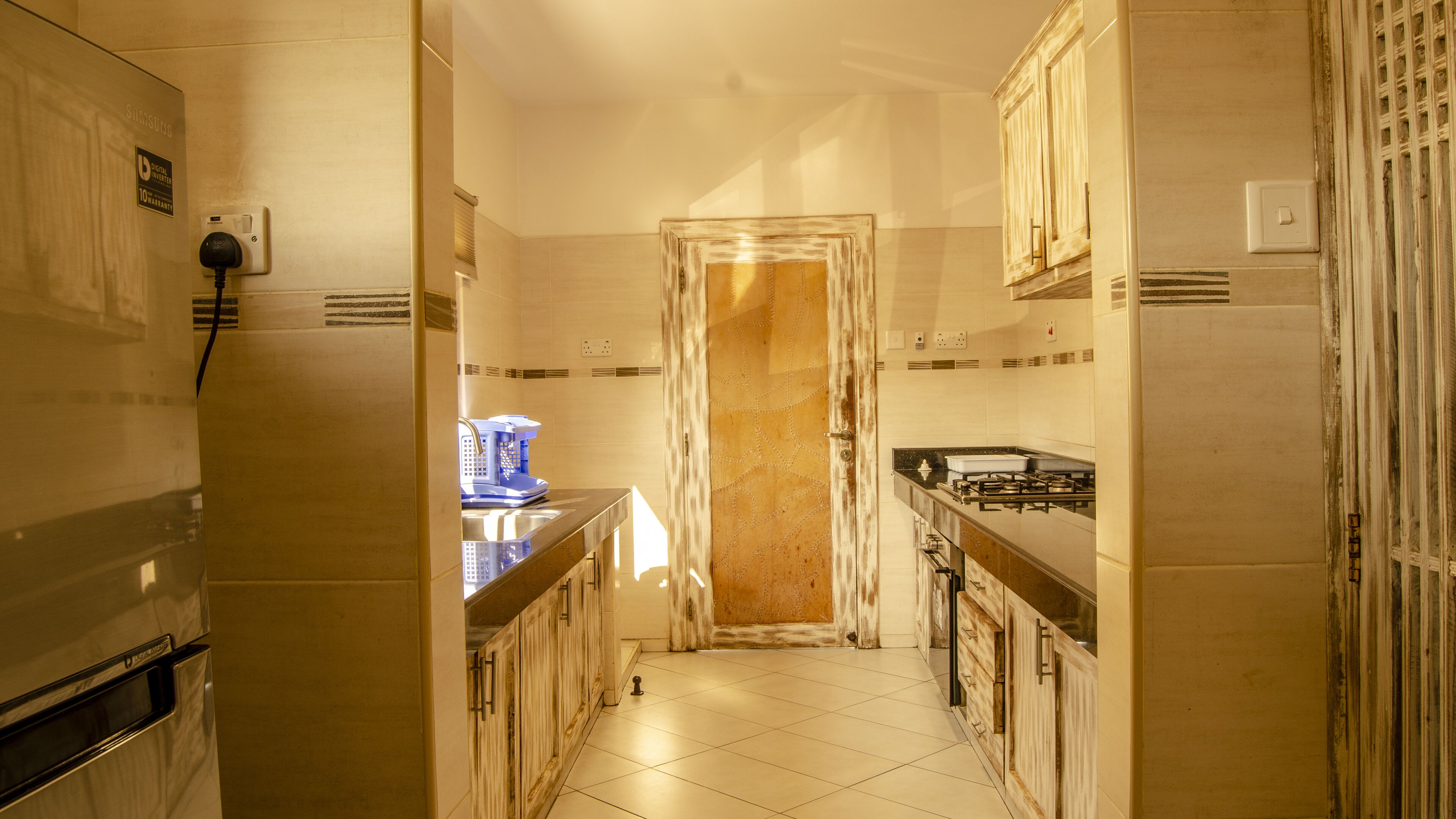 A narrow kitchen with a refrigerator, a coffee machine, and a stove.