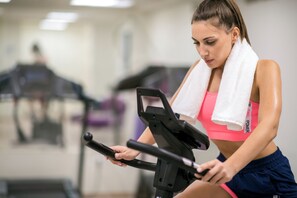 A person using an exercise machine in a gym with mirrors and other equipment in the background. - ibis Styles Athens Routes (Athens)