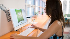 A woman using a desktop computer at a hotel reception desk. - ibis Styles Athens Routes (Athens)
