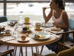 A round wooden table with breakfast items, a glass of water, and a cup.