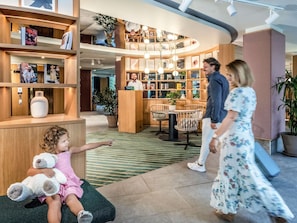 Um hall de hotel com balcão de atendimento, área de estar e espaço de recreação infantil.