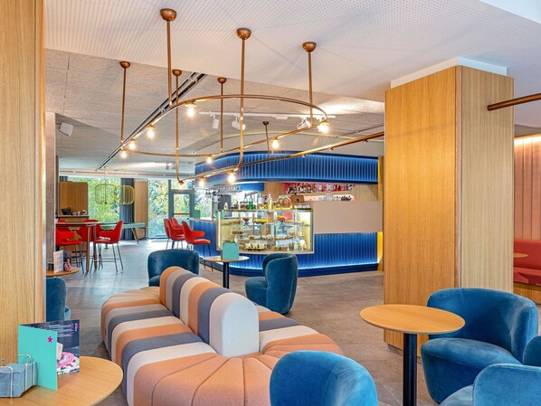 A modern lounge area with a bar, seating arrangements, and a ceiling with exposed ductwork.