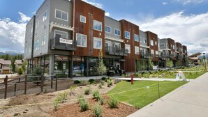 A multi-story building with a mix of commercial and residential units, including a visible storefront with a sign that reads "OPEN HOUSE". - Downtown WP Loft 17 I Huge Hot Tub I Views I Bunk Beds I Game Console I Discounted Attractions (Winter Park)