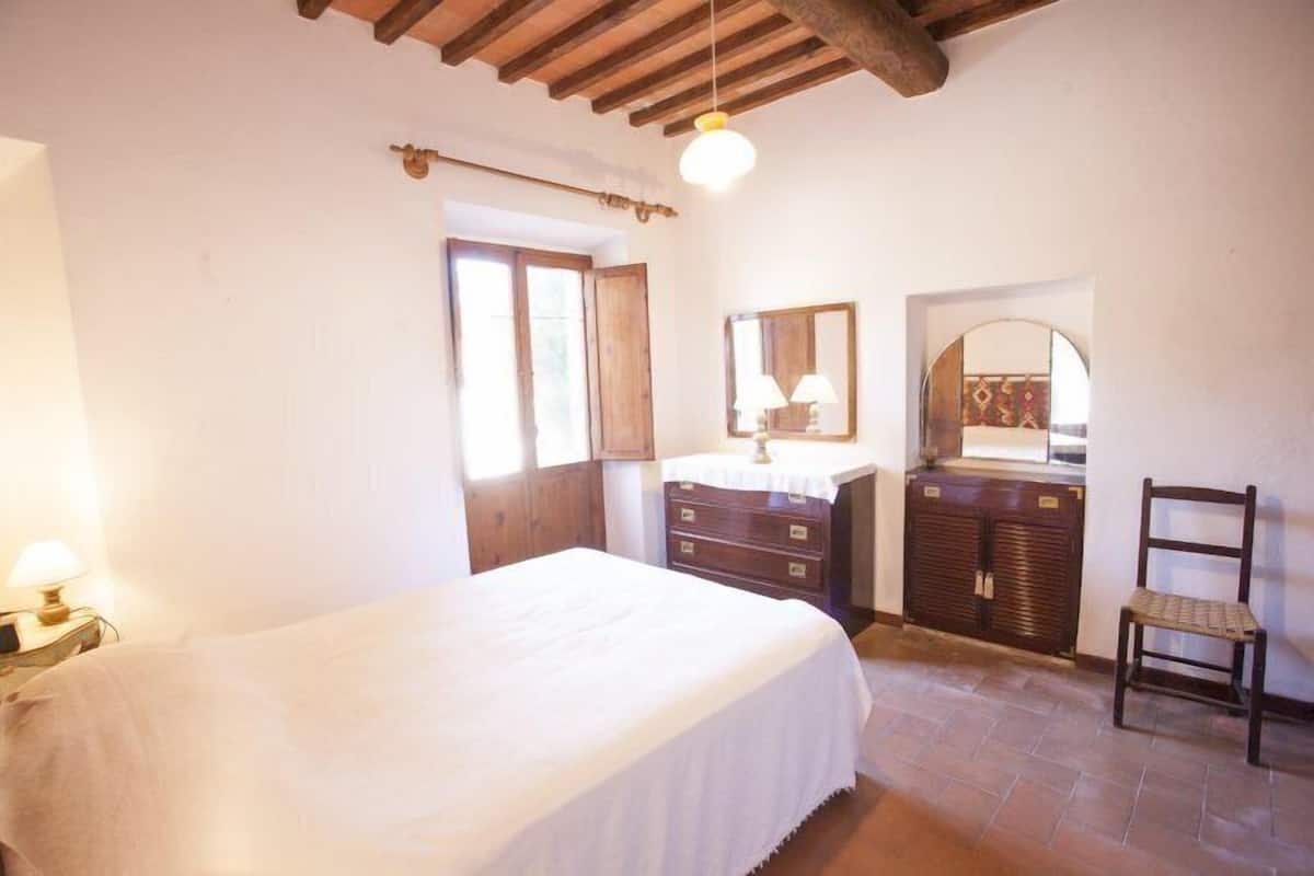 A bedroom with a bed, dresser, chair, and a mirror.