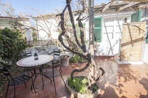 A patio with a round table and chairs, surrounded by a white wall and a wooden fence.