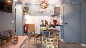 Una cucina compatta con zona pranzo, un forno a microonde, un estintore e un piccolo ripiano con oggetti decorativi.