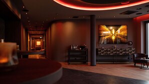 A modern lobby with a curved ceiling, a seating area with a table, and a large wall-mounted artwork. - Qube Hotel Bahnstadt (Heidelberg)