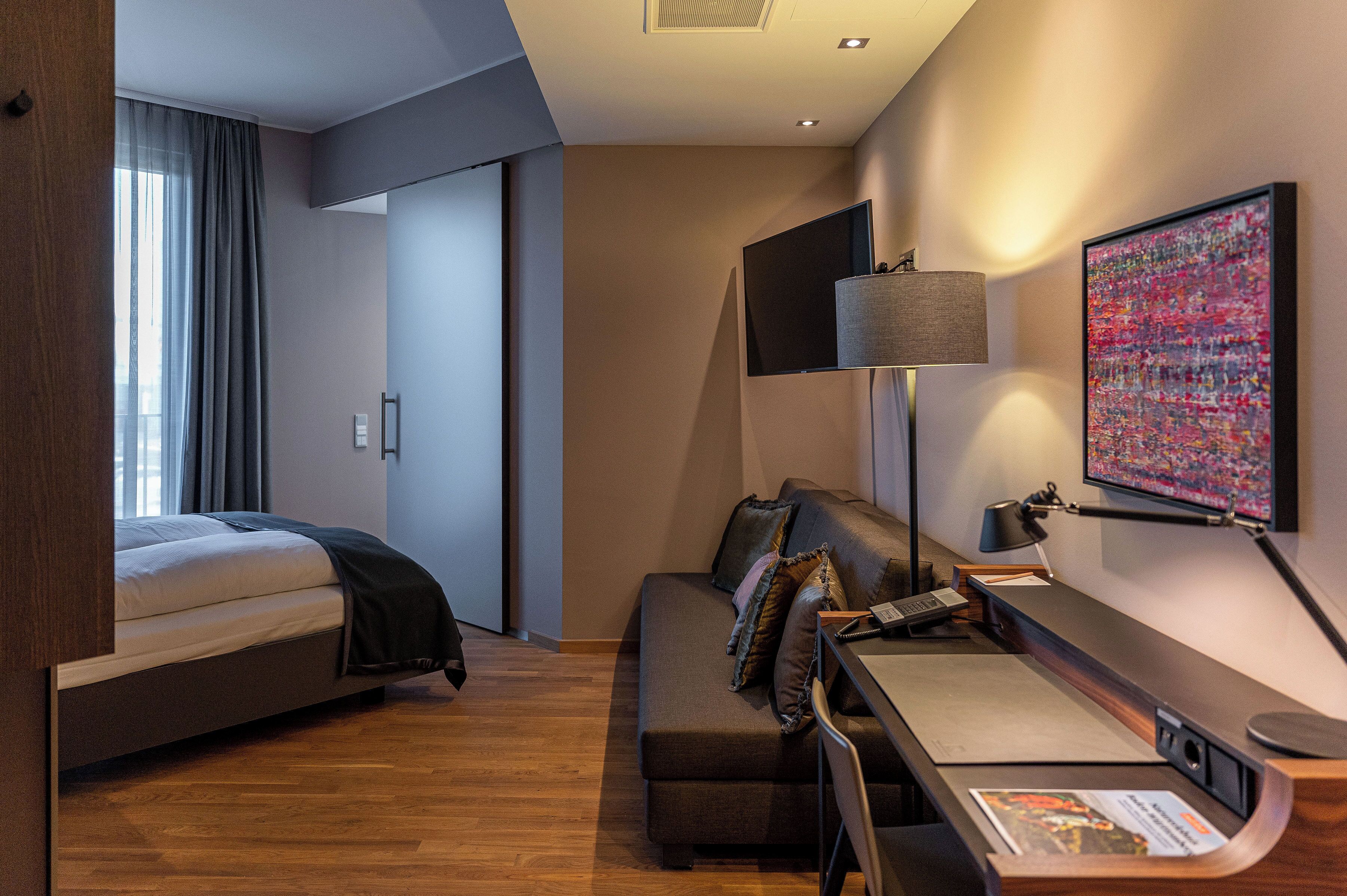Une chambre d’hôtel moderne équipée d’un lit, d’un canapé, d’un bureau et d’une télévision.