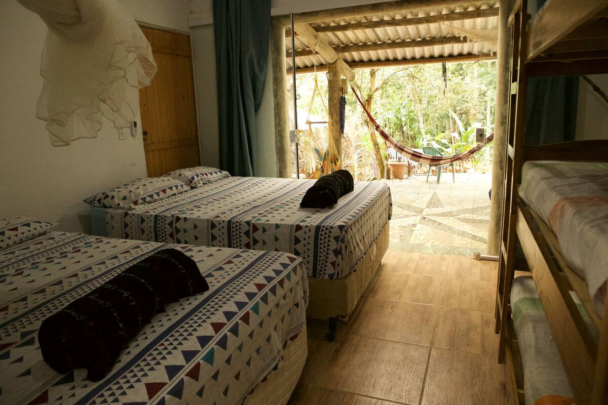 A room with two beds, a hammock, and a view of the outdoors.
