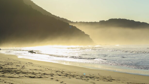 A beach with waves and a mountain in the background. - Sitio Simple Life - Hostel (Ubatuba)