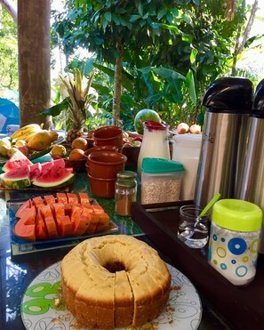 A table with various fruits, a bottle of milk, a thermos, and a jug with a straw. - Sitio Simple Life - Hostel (Ubatuba)