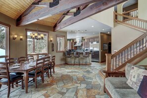 A spacious dining area with a stone floor, wooden furniture, and a view of the outdoors.