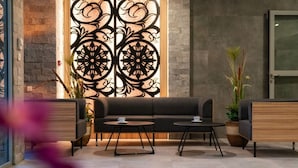 Un espace de détente moderne comprenant un canapé et deux petites tables, un panneau décoratif mural et des plantes en pot.