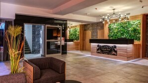 Un espace d’accueil moderne comprenant un comptoir de réception, un coin salon et un escalier menant à l’étage supérieur.