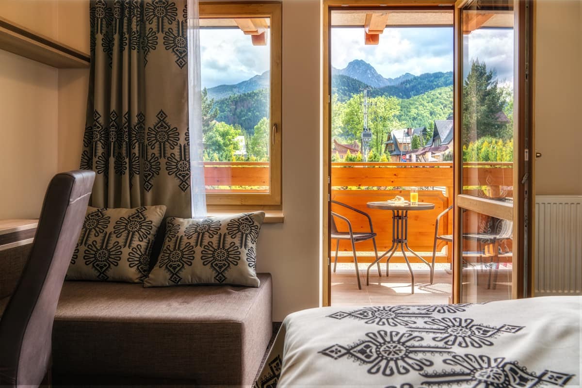 Een kamer met een bed, een slaapbank en een balkon met een tafel en stoelen.