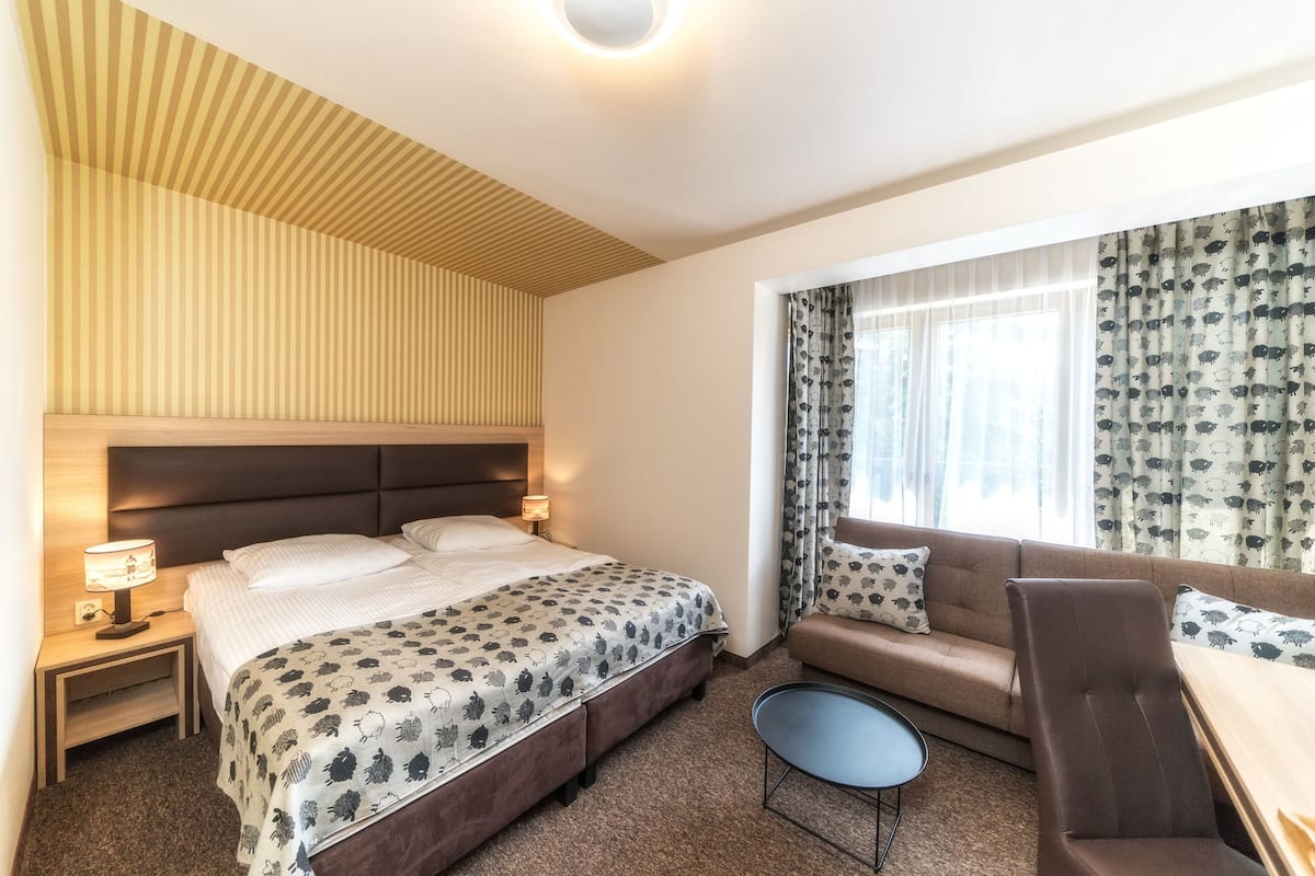 Een hotelkamer met een bed, een bank, een tafeltje en een raam met gordijnen.