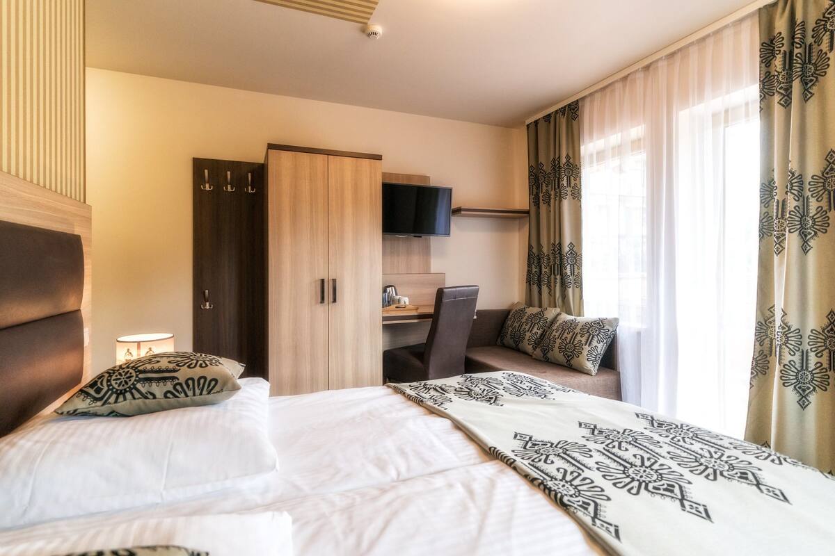 Een hotelkamer met een bed, een bureau, een televisie en een kledingkast.