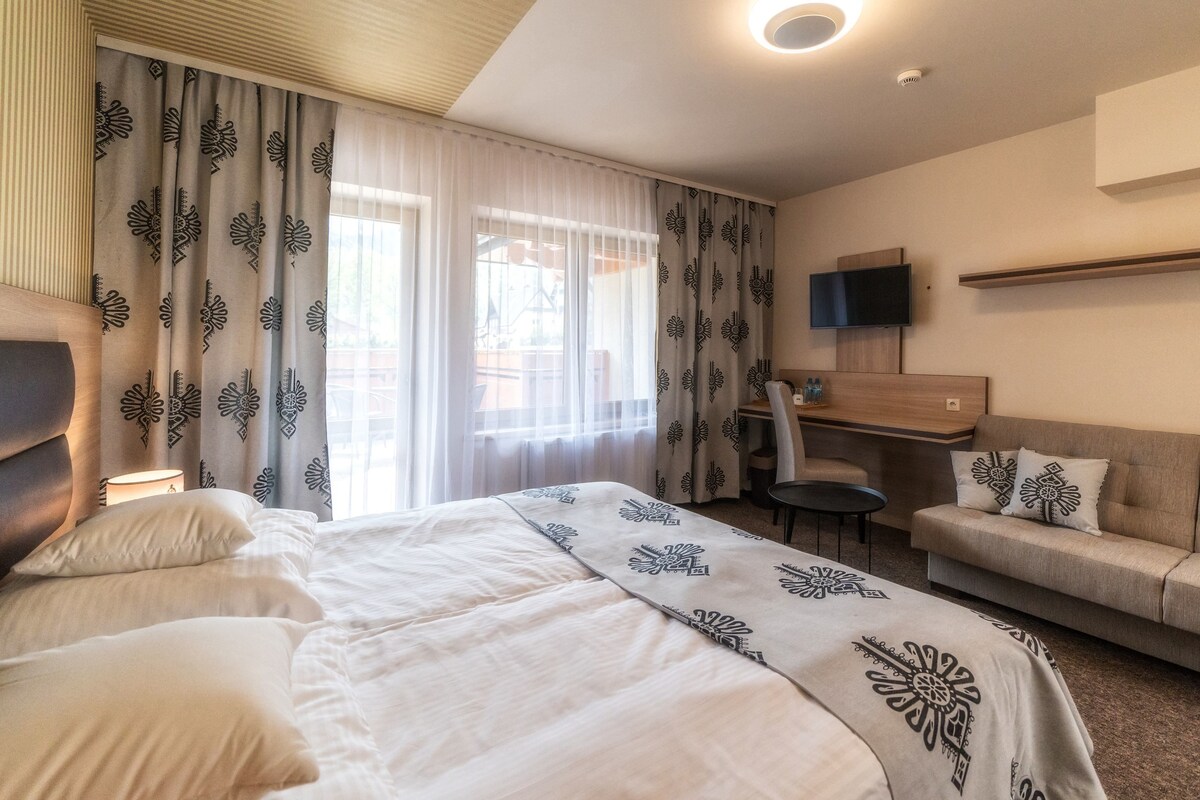 Een hotelkamer met een bed, een bank, een bureau en een televisie.