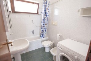 Une petite salle de bain avec un lavabo, des toilettes et un lave-linge.
