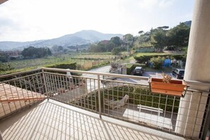 Un balcon offrant une vue sur un paysage rural, avec des champs et des collines à l’horizon.