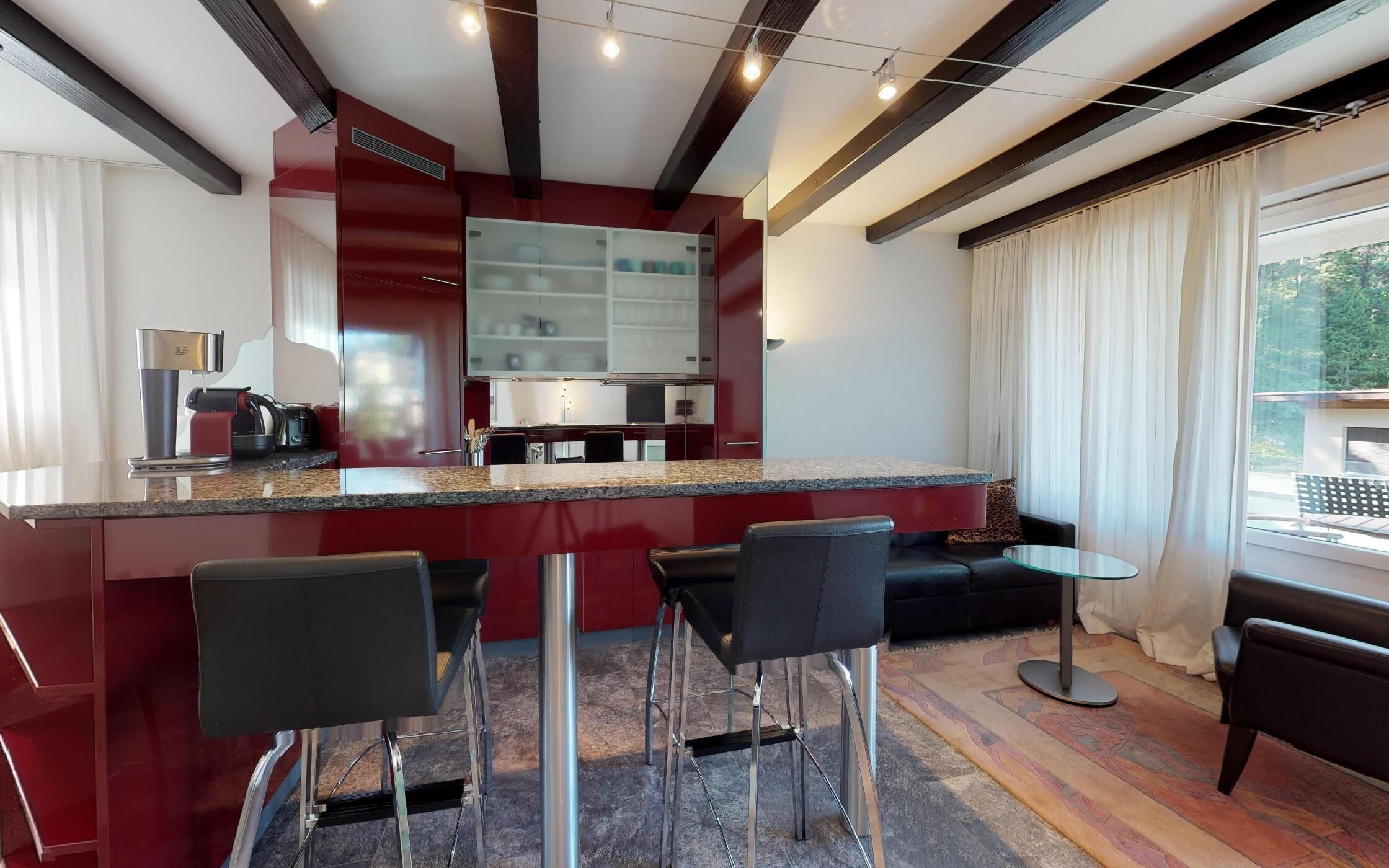 Una cocina moderna con barra, asientos y vistas al exterior.