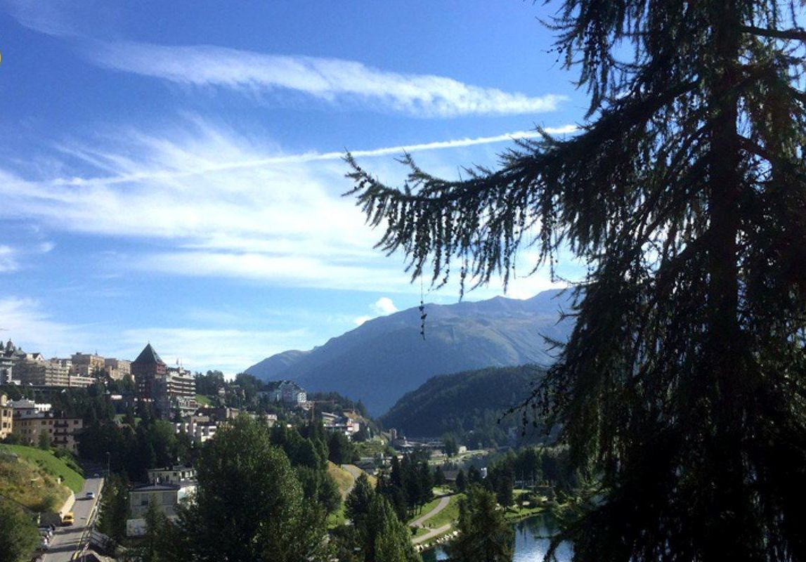 A cityscape with a river, mountains, and a clear sky.