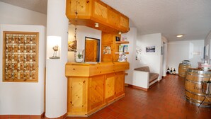 A reception area with a wooden counter, a wall-mounted telephone, and a bulletin board with numbered slots. - T3 Hotel Mira Val (Flims)