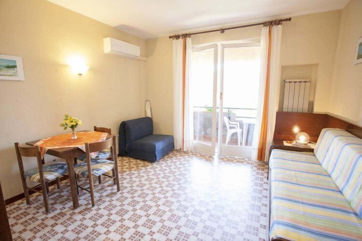 Quarto com mesa de jantar, cadeiras, sofá e varanda com vista.