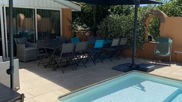 Un'area piscina con zona relax coperta, lettini e piscina.