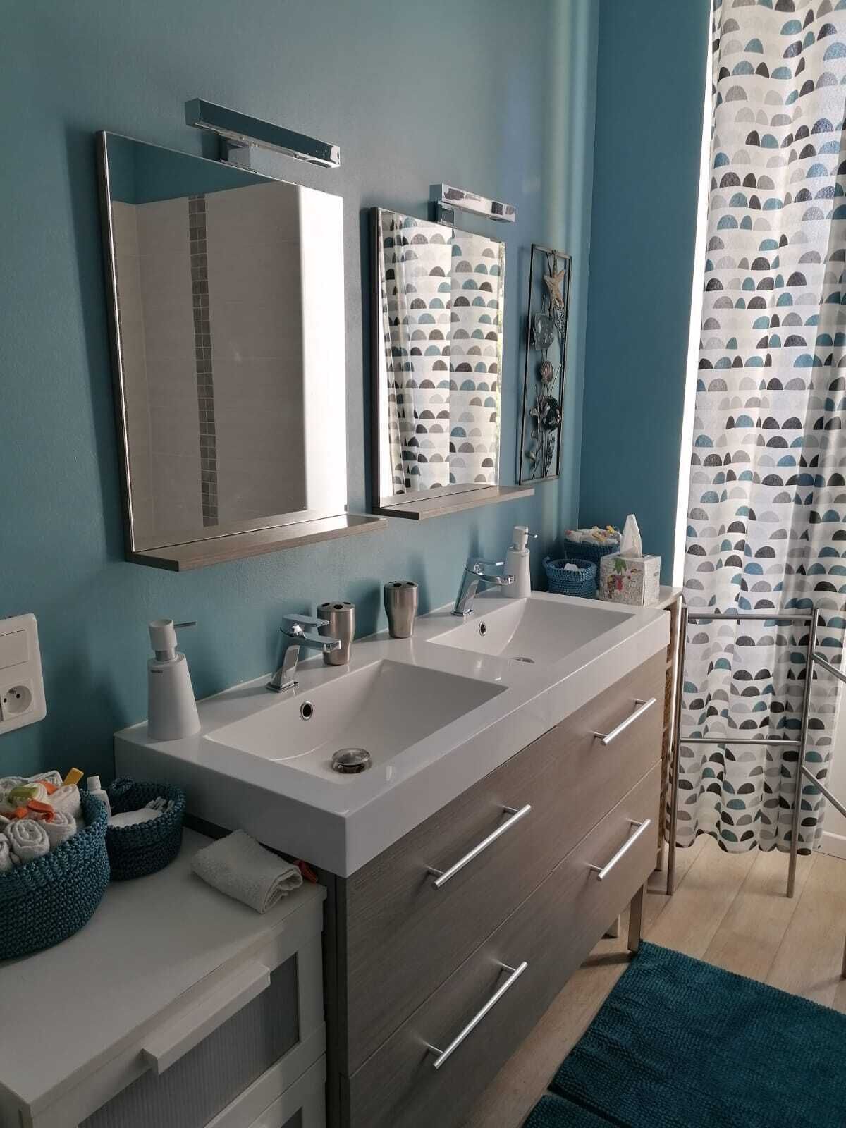 Un baño con dos lavabos, un espejo y una cortina de ducha.