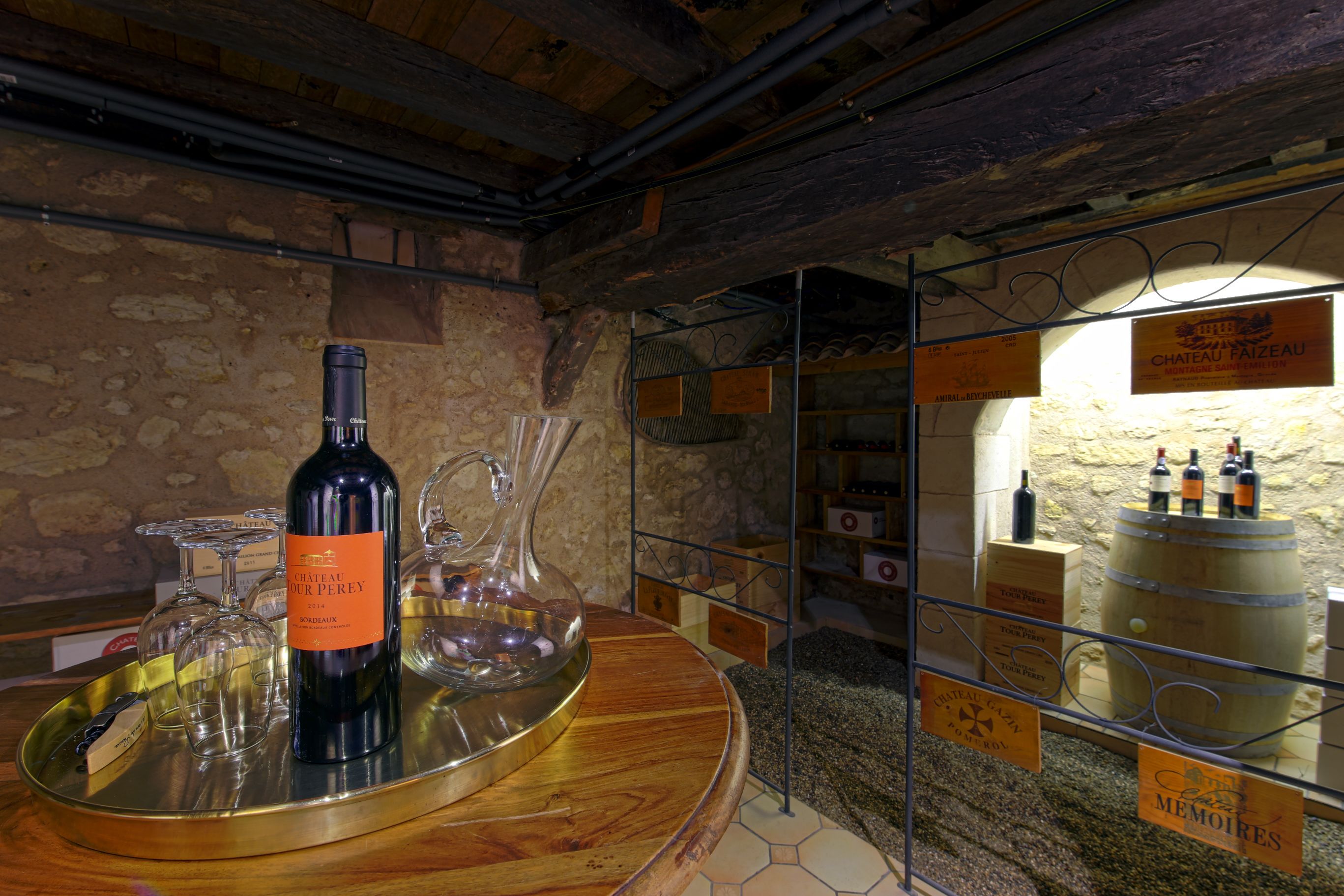 A wine tasting area with a wooden table displaying a bottle of Chateau Perrey 2018, wine glasses, and a wine barrel.