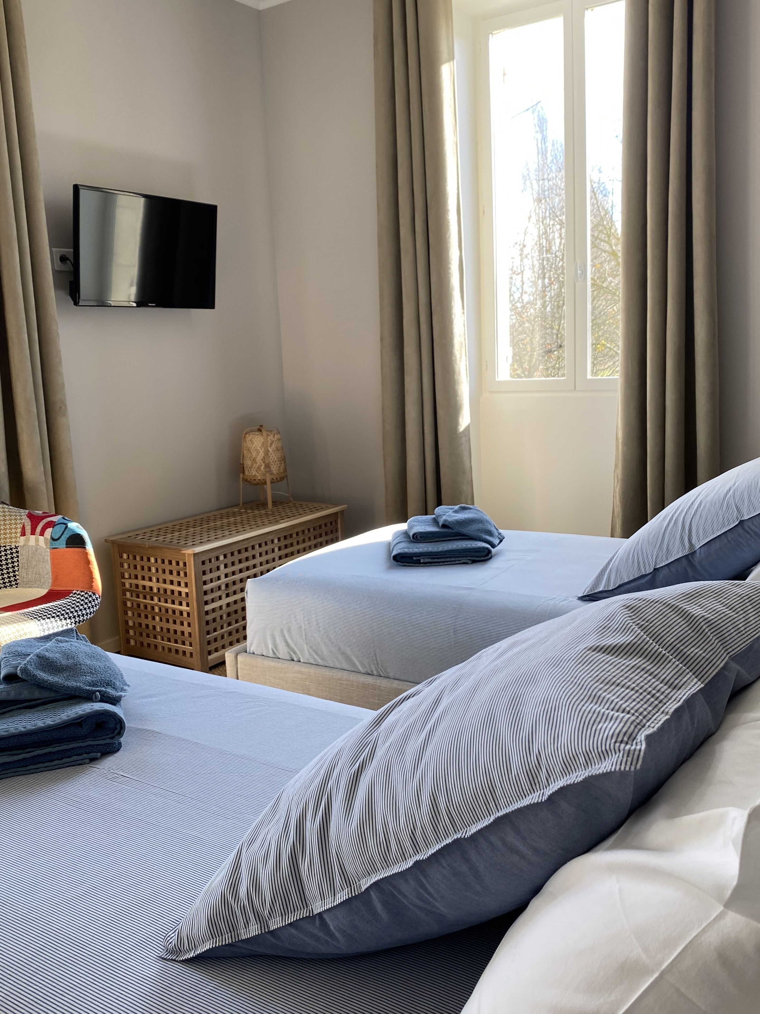 Habitación de hotel con dos camas, un televisor de pantalla plana, una mesita y una ventana con cortinas.