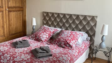 A neatly made bed with floral bedding, a tufted headboard, and two bedside lamps.