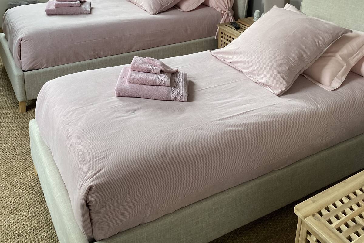 Een slaapkamer met twee bedden, elk voorzien van passende kussens en opgevouwen handdoeken.