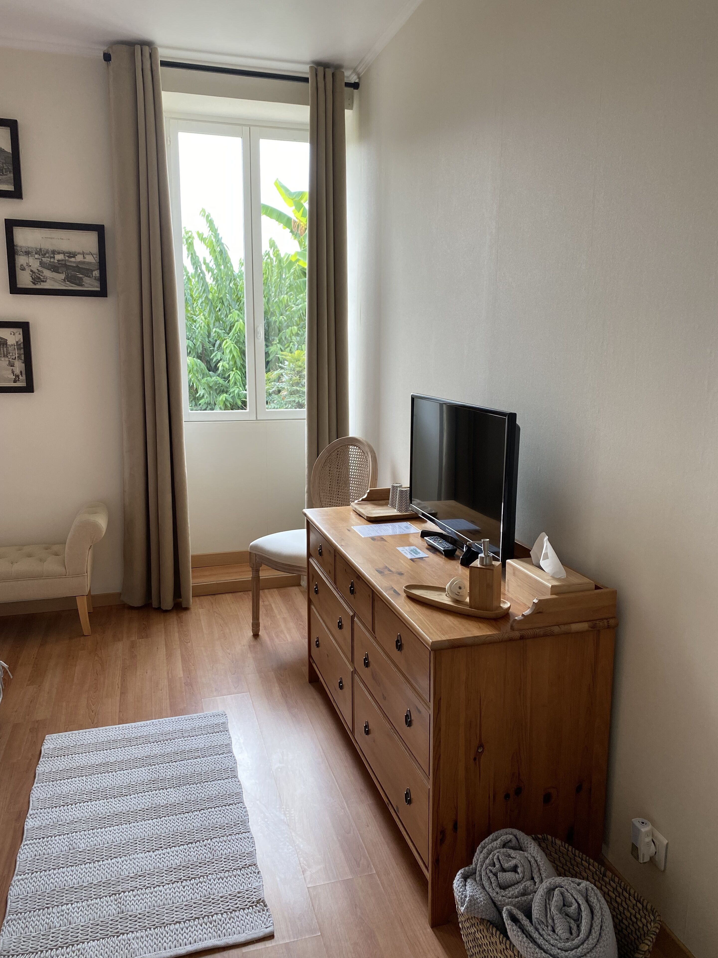 Ein Zimmer mit einem Holztisch, einem Stuhl, einem Fernseher und einem Vorhangfenster.