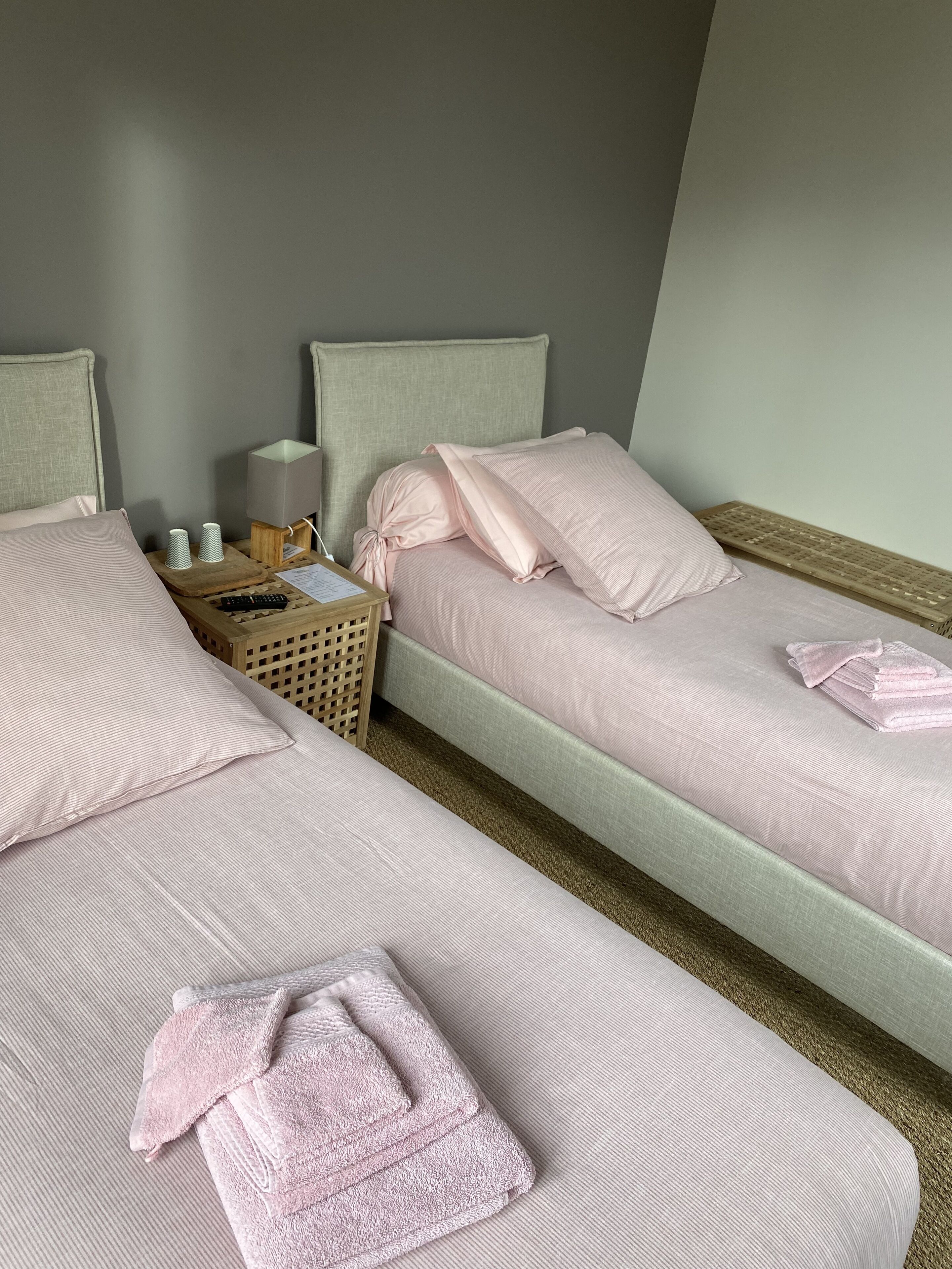 A twin room with two beds, a nightstand, a lamp, and a keyboard.