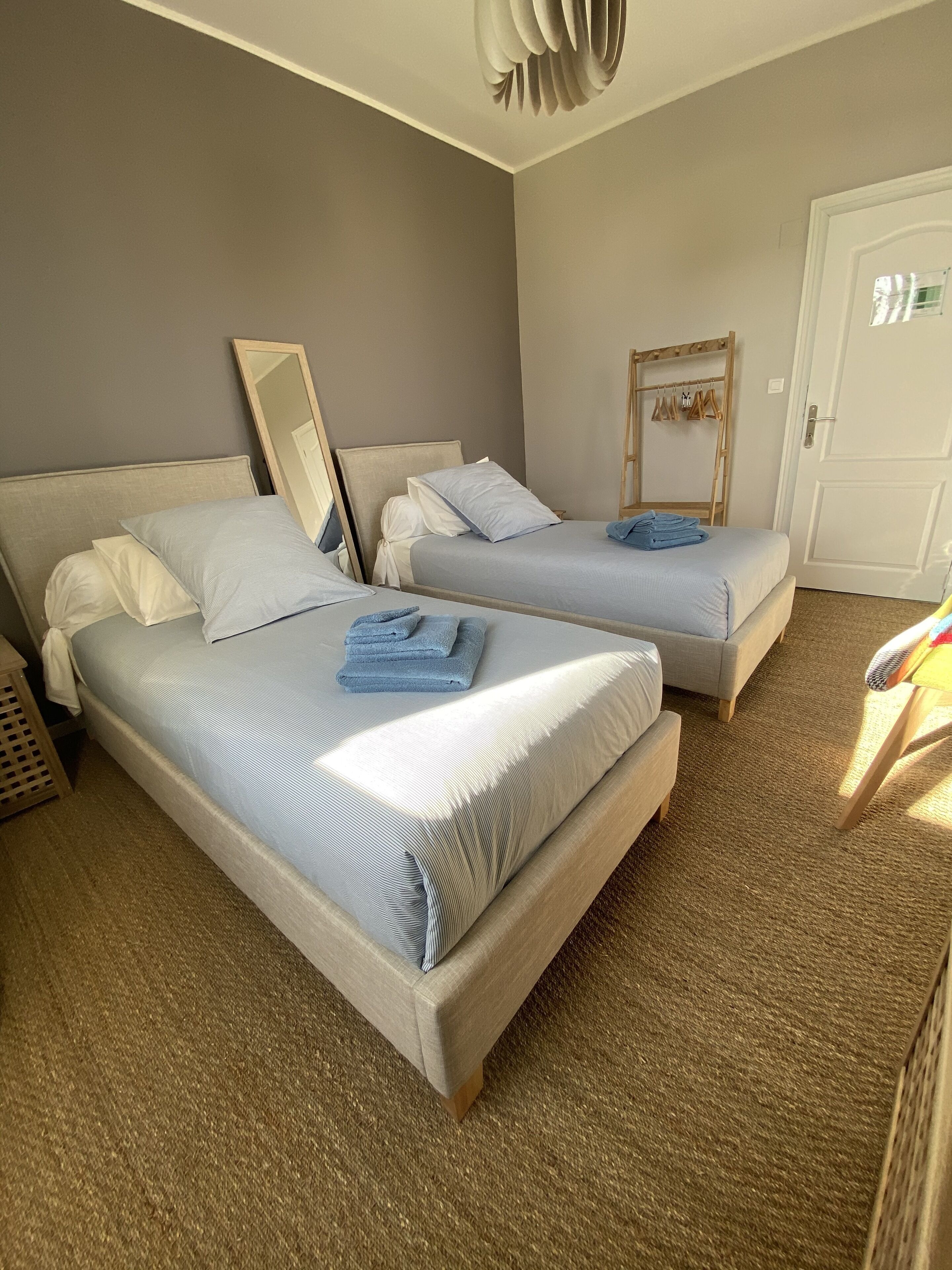 Habitación de hotel con dos camas, un armario, un espejo y una puerta.