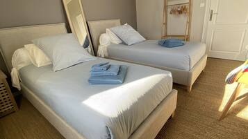 Habitación de hotel con dos camas, un armario, un espejo y una puerta.