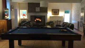 A living room with a pool table, a fireplace, and comfortable seating.