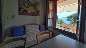A room with a wooden sofa, a table, and a painting of a fish on the wall. - Villa Vosilla (Opatija)