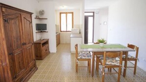 A dining area with a table, chairs, and a television on a stand. - Appartamenti Le Mimose (Capoliveri)