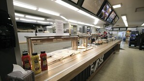 A buffet counter with condiment bottles, a tissue box, and a menu sign. - Hotelli Toivola (Kemi)