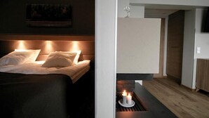 A modern bedroom with a bed, a bedside table with candles, and a painting on the wall. - Hotelli Toivola (Kemi)