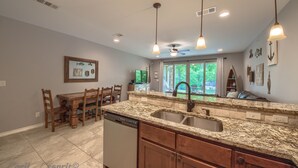 A kitchen with granite countertops, wooden cabinets, a dishwasher, and pendant lighting. - Rio Refuge Rg 105 2 Bedroom Condo by RedAwning (New Braunfels)