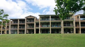 A multi-story hotel with balconies, outdoor seating, and a grassy lawn. - Rio Refuge Rg 105 2 Bedroom Condo by RedAwning (New Braunfels)