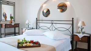 Un letto rifatto con lenzuola bianche, un vassoio con cibo e bevande, e due opere d'arte appese alla parete.