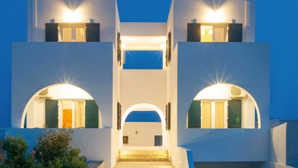 Un edificio moderno con una scalinata centrale che conduce all'ingresso, circondato da pareti bianche e tocchi di blu.