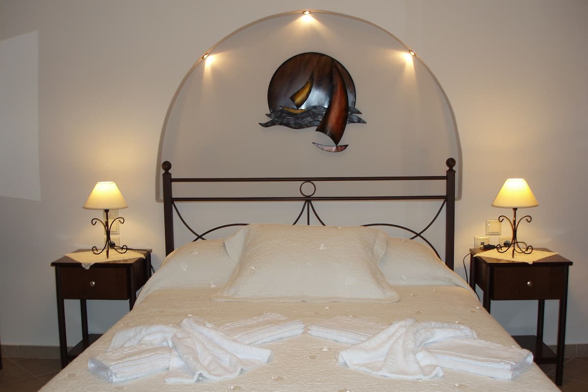 A neatly made bed with towels, two bedside lamps, and a wall art piece above the bed.